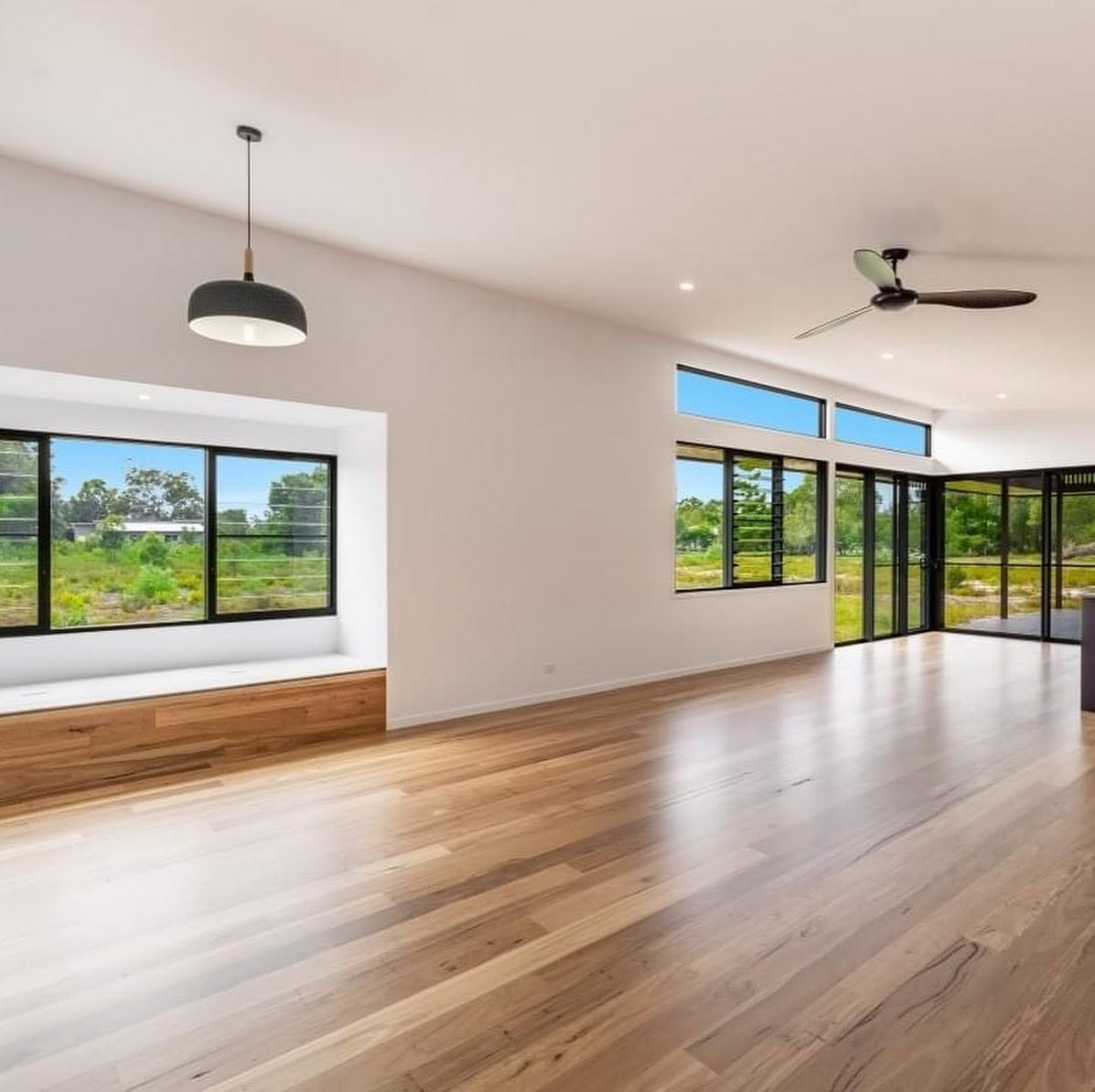 Open-plan living area with timber flooring and freshly painted white walls by R J Britt Painting in Lismore, NSW