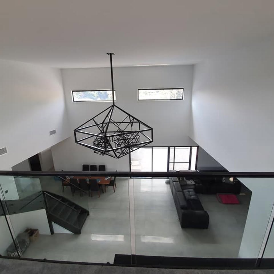 Double-height living and dining space with freshly painted white walls and black feature pendant painted by R J Britt Painting in Tweed Heads