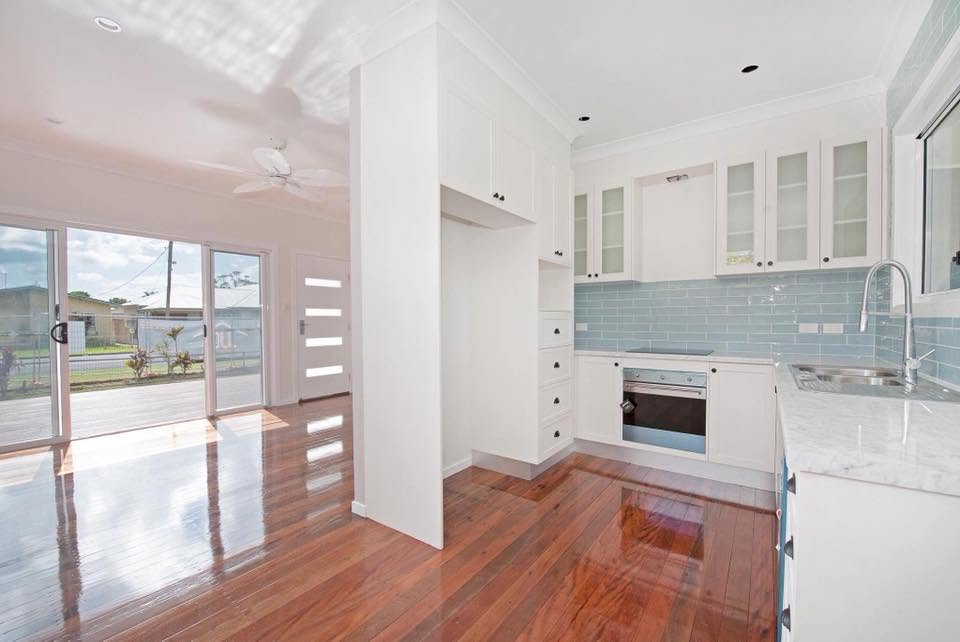 Freshly painted white kitchen with blue tiled splashback and polished timber floors by R J Britt Painting in Yamba