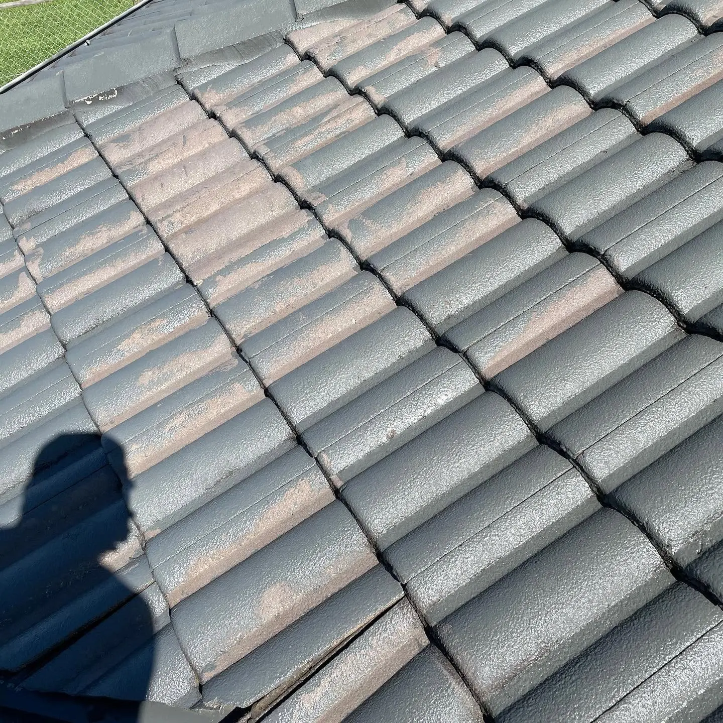 Concrete tile roof mid-restoration with fresh charcoal roof paint applied by R J Britt Painting in Lismore, NSW