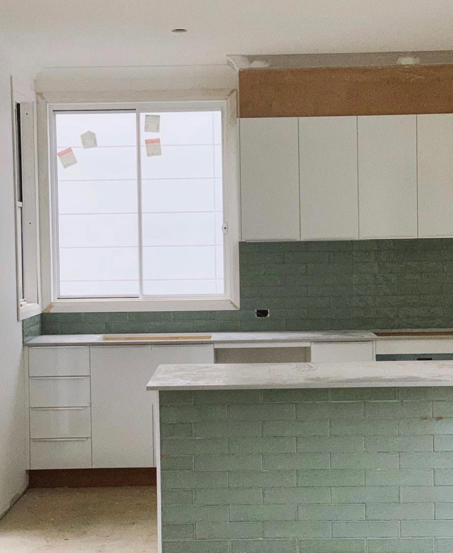 Interior painting of a kitchen with white walls, cabinetry and green tiled splashback by R J Britt Painting in Lismore, NSW