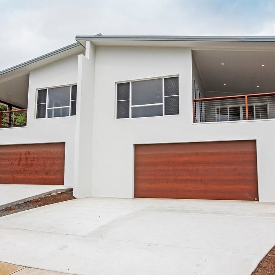Modern two-storey home with freshly painted white rendered exterior and timber garage doors by R J Britt Painting in Byron Bay