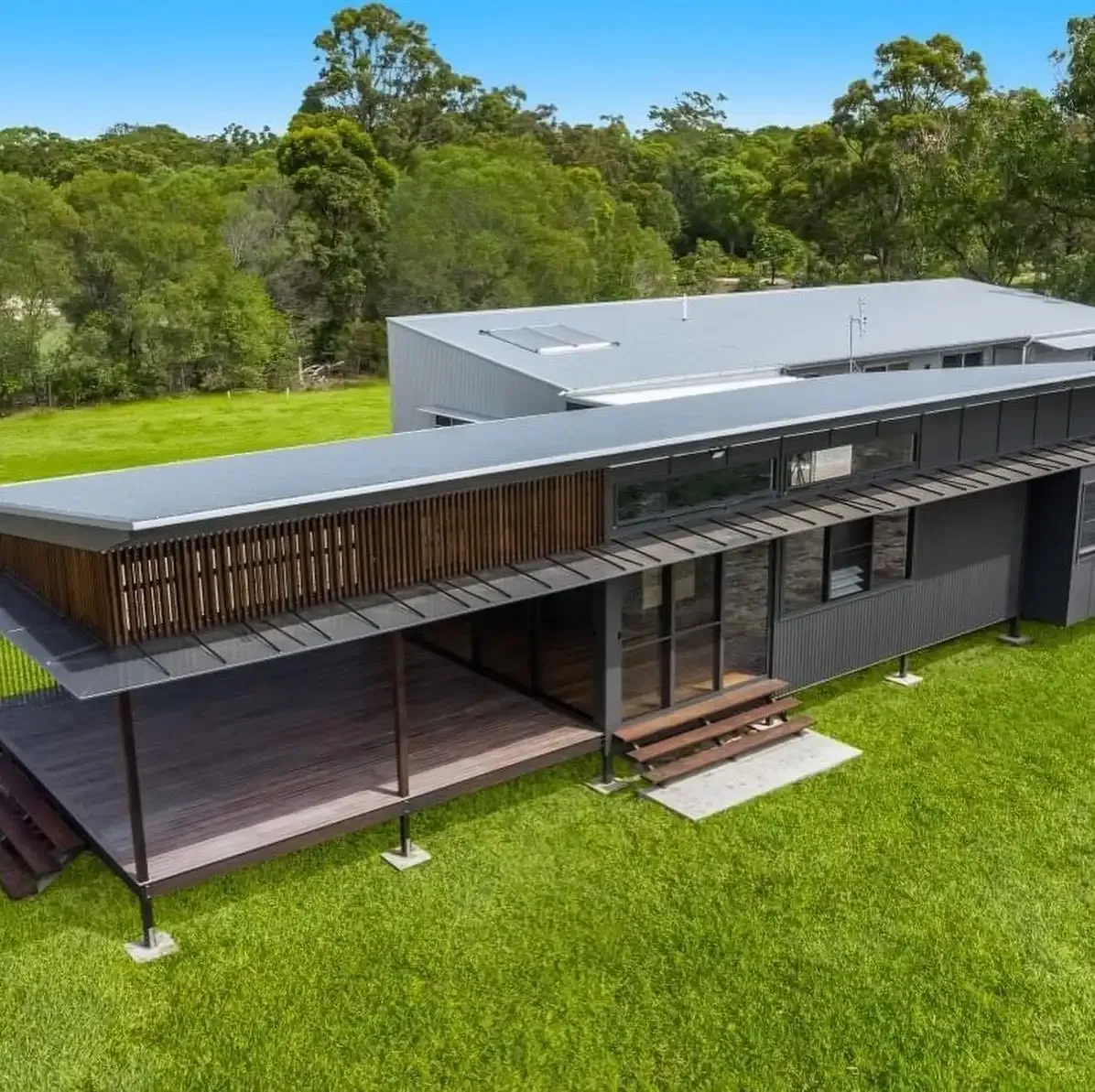 Aerial view of a freshly coated charcoal metal roof on a modern rural home with timber deck by R J Britt Painting in Lismore, NSW