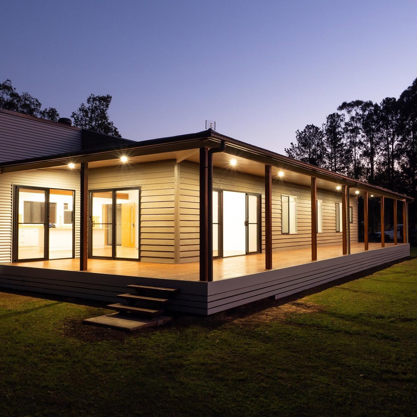 Freshly painted weatherboard home with a timber deck lit at dusk by R J Britt Painting, painters in Ballina