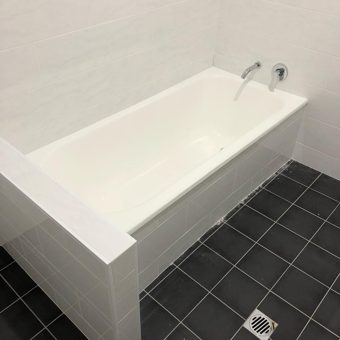 Freshly finished bathroom with white tiled walls, built-in bath and charcoal floor tiles by R J Britt Painting in Casino