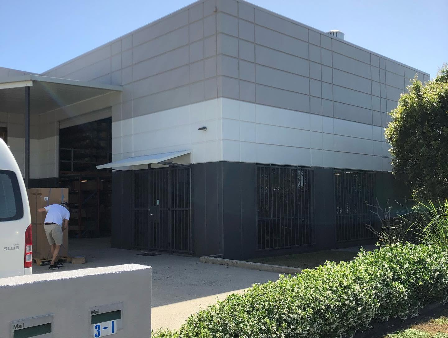 Commercial warehouse and office facade repainted in white and charcoal by R J Britt Painting in Lismore, NSW